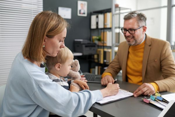 young woman sitting with her little son filing documents social benefits