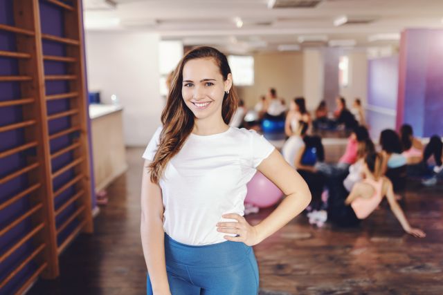 young smiling caucasian brunette sportswear holding hand hip posing